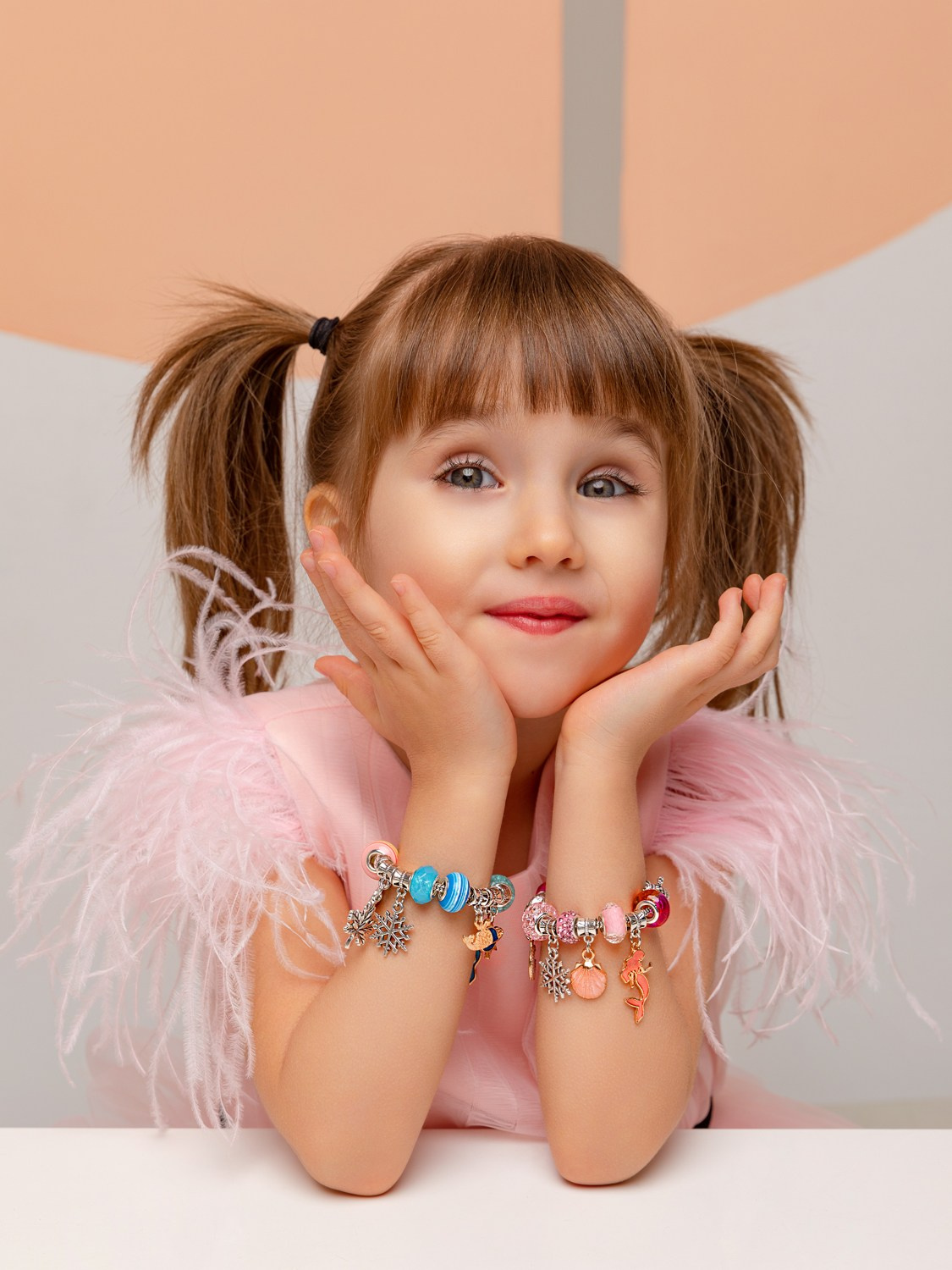 Девочка демонстрирует два браслета, одетые на обе руки.