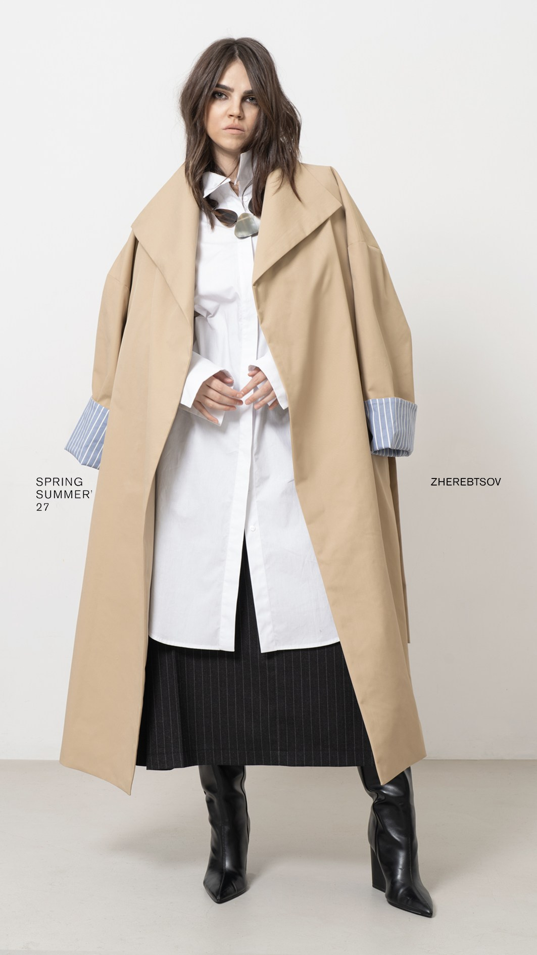 Fashion lookbook ZHEREBTSOV — бежевый тренч поверх белой удлинённой рубашки и тёмной юбки, студийный кадр в полный рост