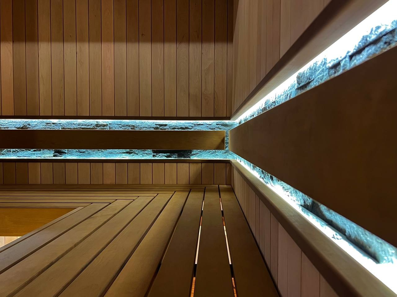 Просторная сауна в Сертолово из термоольхи с интеграцией можжевеловых линий и большого количества натурального камня. SaunaTopMasters