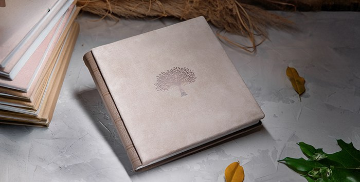 Фотокнига ручной работы в кожаном переплете на сером фоне с декоративными элементами.