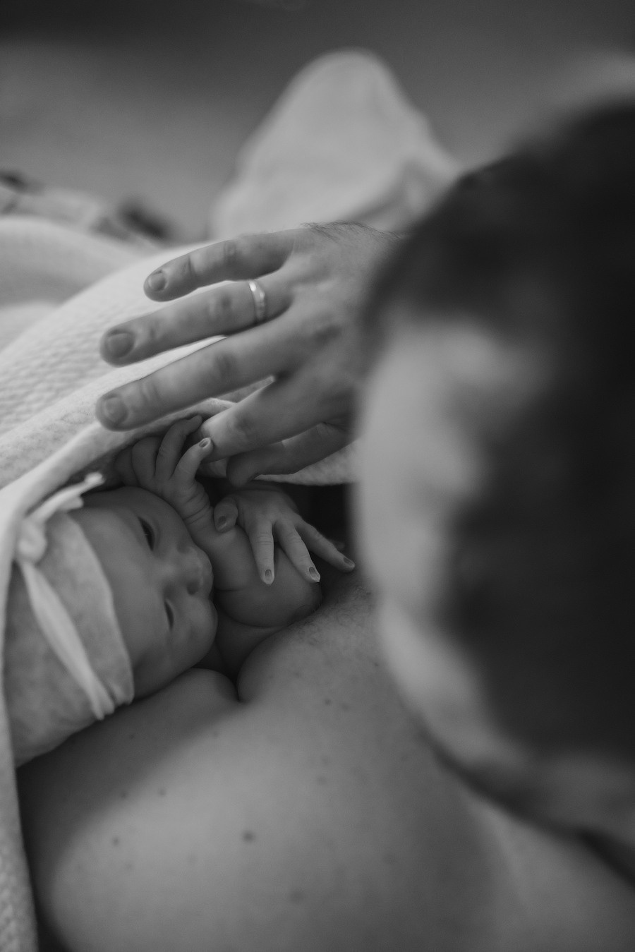 Black and white photo of newborn baby resting on mother, tender family photo by Anny Smirnova