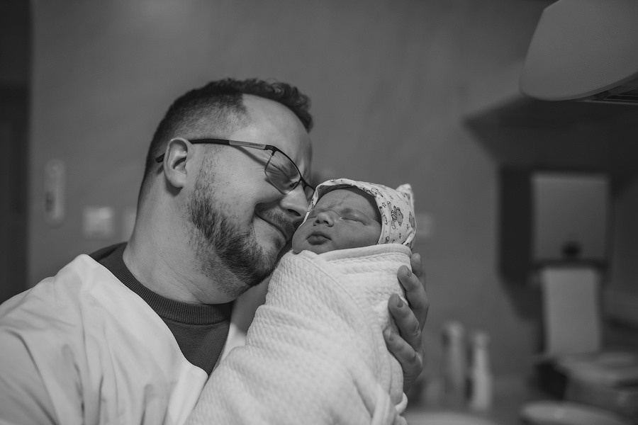 Black and white, new dad holding newborn baby in arms. Austin birth photographer Anny Smirnova
