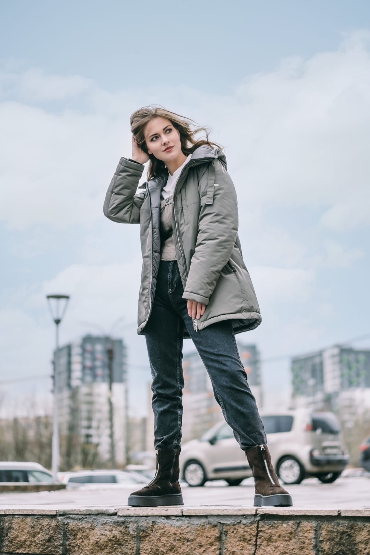 Девушка в куртке и джинсах на фоне города