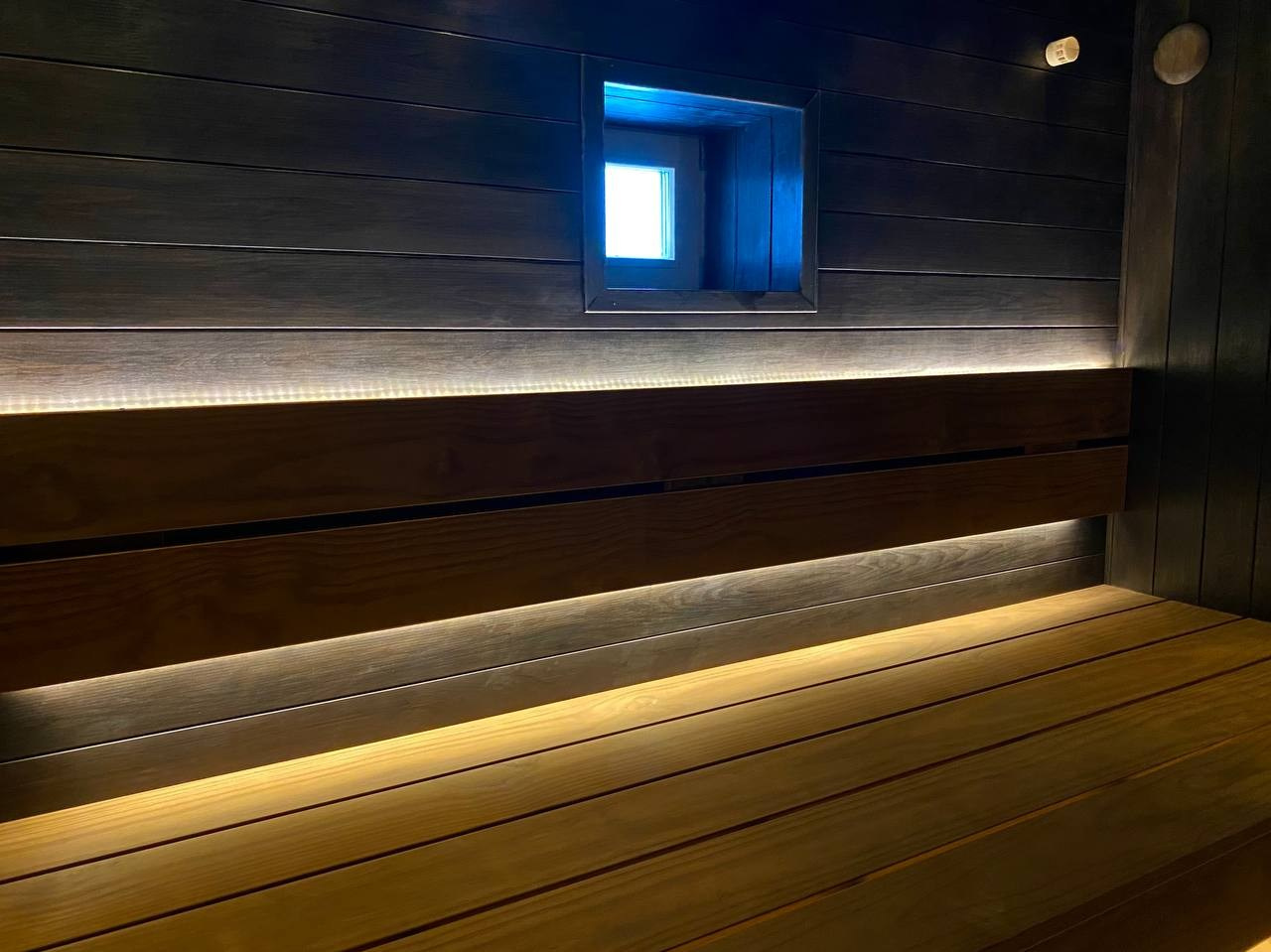 Чёрная «Богатырь-баня» в Боровске: четыре уровня полков, белый кварцит в противопожарном углу и кастомная газовая печь в центре внимания. SaunaTopMasters