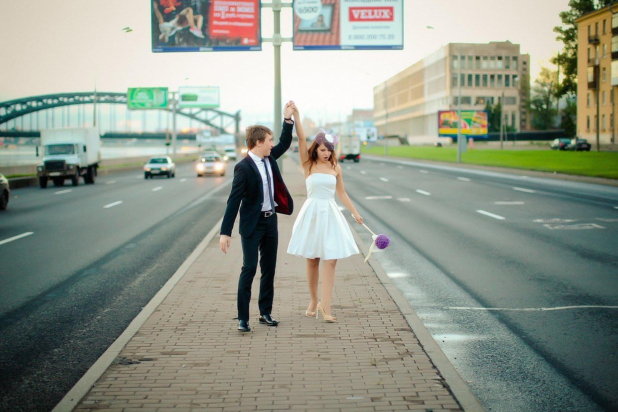 жених и невеста в коротком платье идут по центру проезжей части