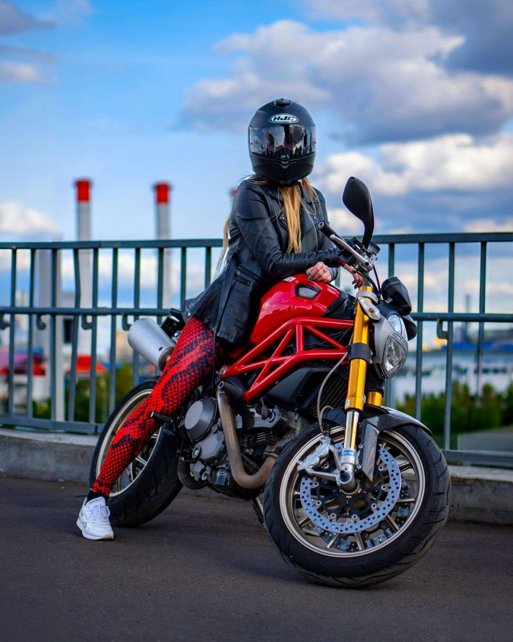 мотоциклистка сидит на красном мотоцикле ducati с видом на небоскребы
