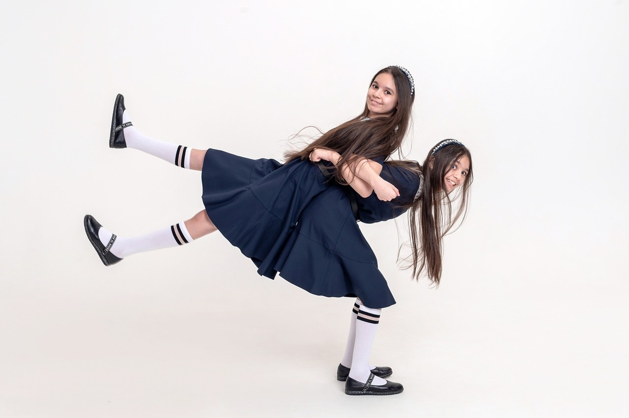 Девочки в школьной форме поднимают друг друга по очереди для красивого фото.