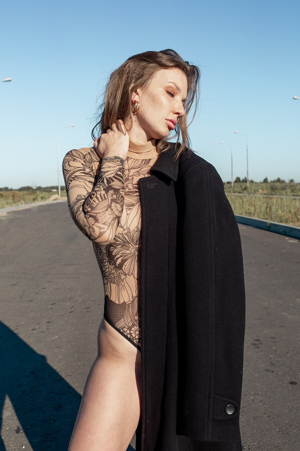 Портрет девушки на дороге в боди с пальто которое закрывает пол тела