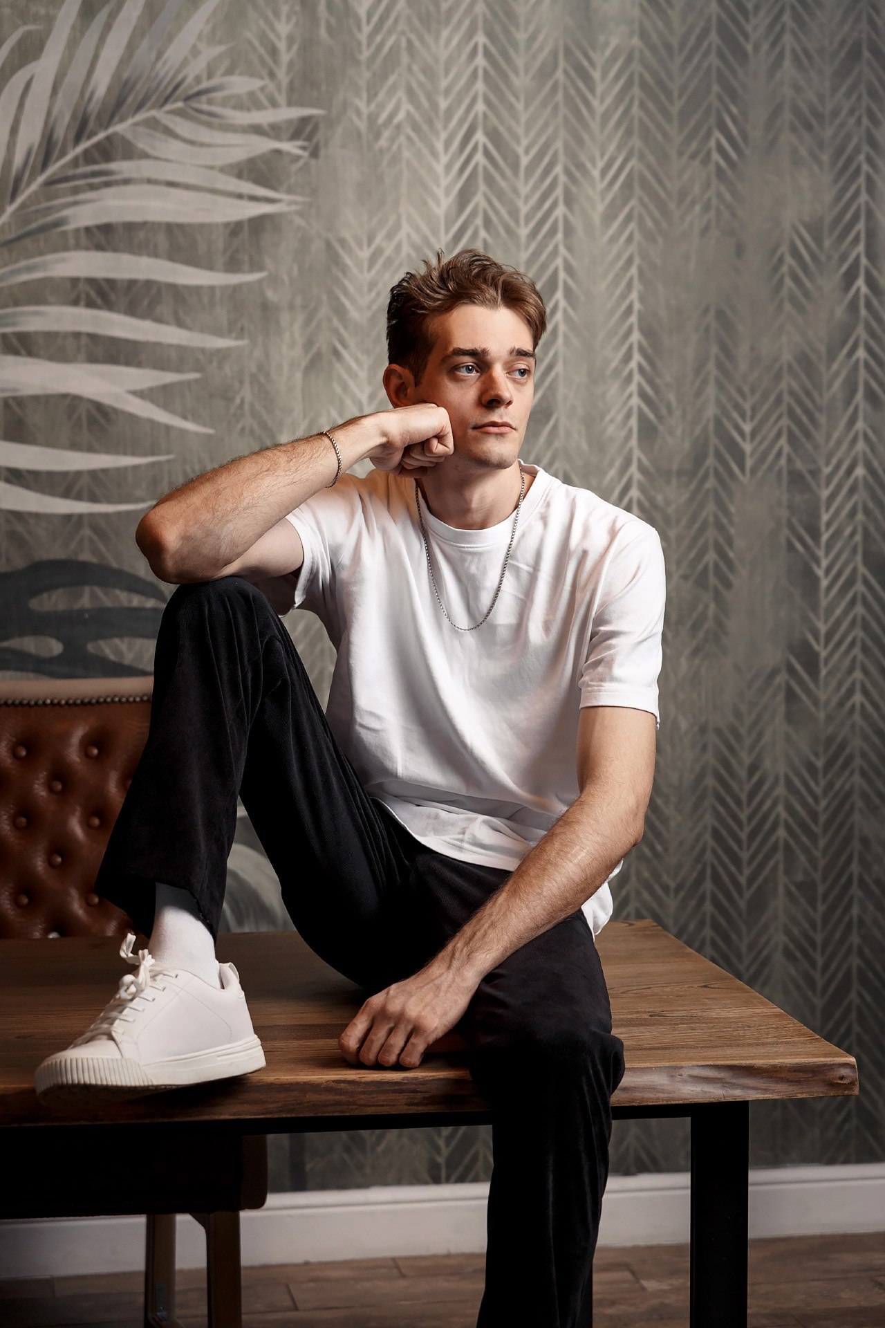 Парень в белой футболке сидит на столе