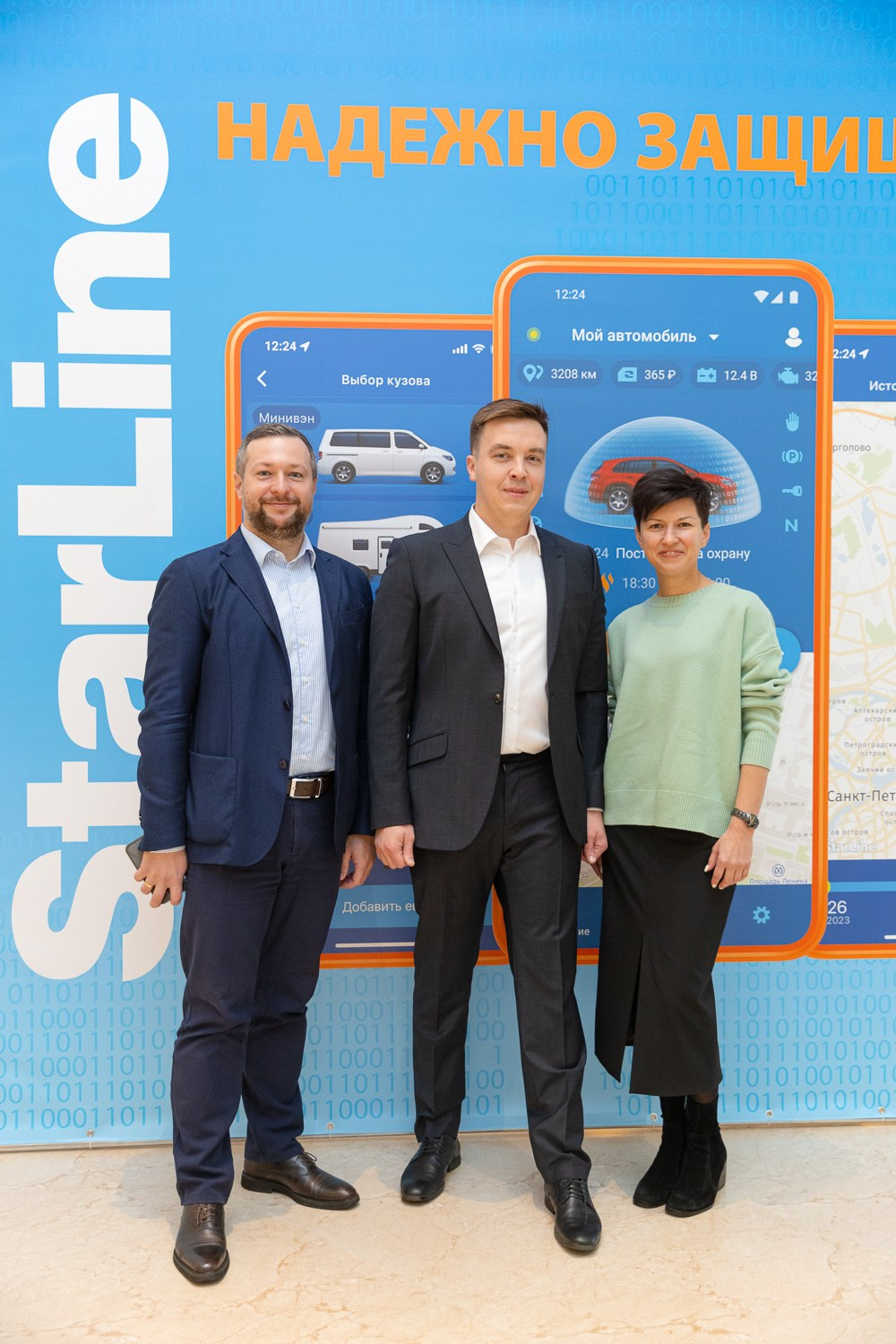 Трое людей позирует фотографу стоя на фоне прэссвола старлайн