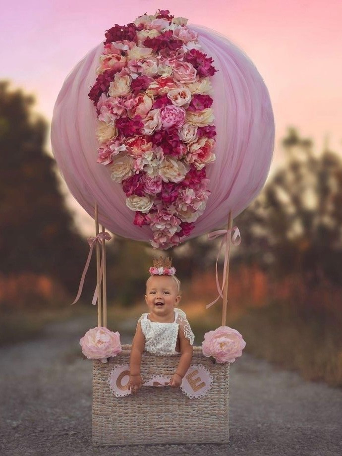 Ребенок на розовом воздушном шаре, декорированном цветами