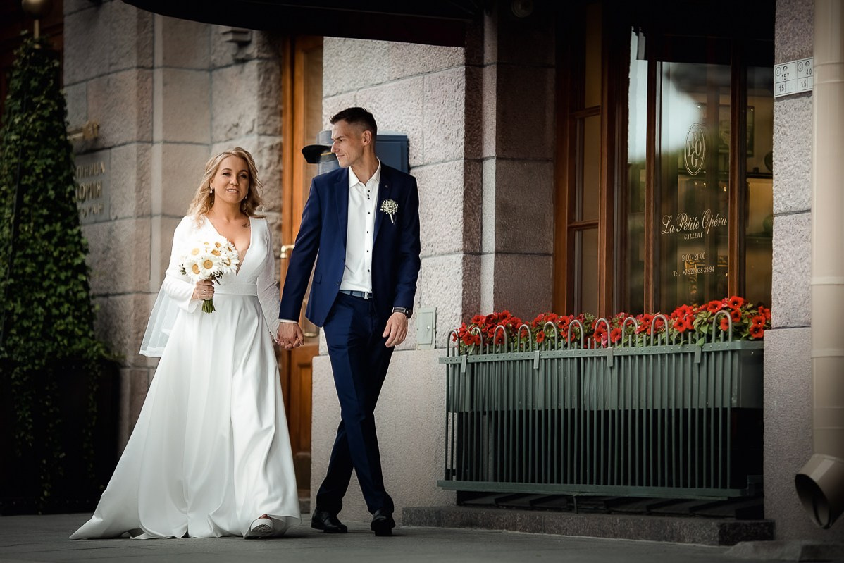 Жених и невеста прогуливаются возле гостиницы "Астория" в Санкт-Петербурге. Горизонтальный ростовой кадр.