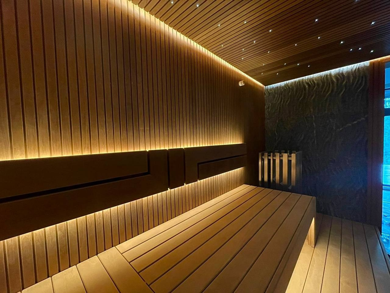 Сауна на Медном Озере из термоольхи «рейка», с тёплой подсветкой, звёздным небом и эффектным IKI Monolith на фоне итальянского камня. SaunaTopMasters