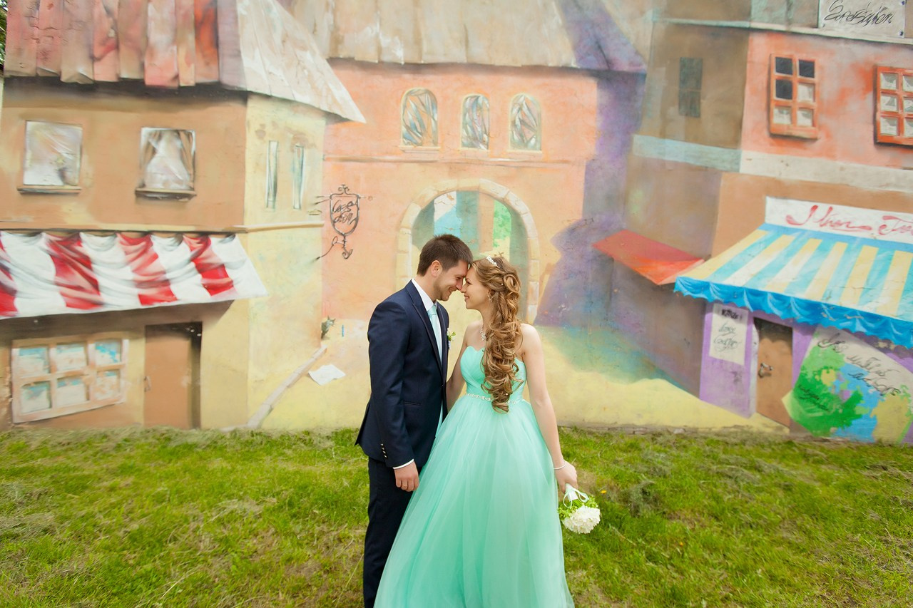 невеста с букетом в платье цвета тиффани обнимает жениха на фоне граффити с изображением Парижа