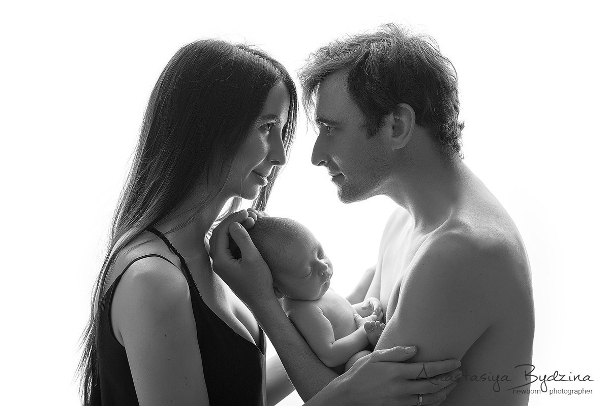 Мама с папой нежно держат новорожденного сына