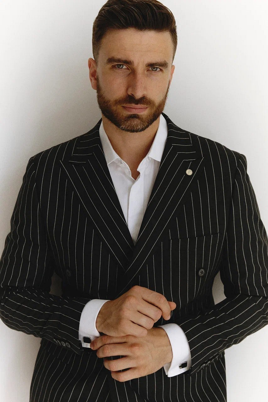Мужчина с бородой в черном полосатом пиджаке и белой рубашке