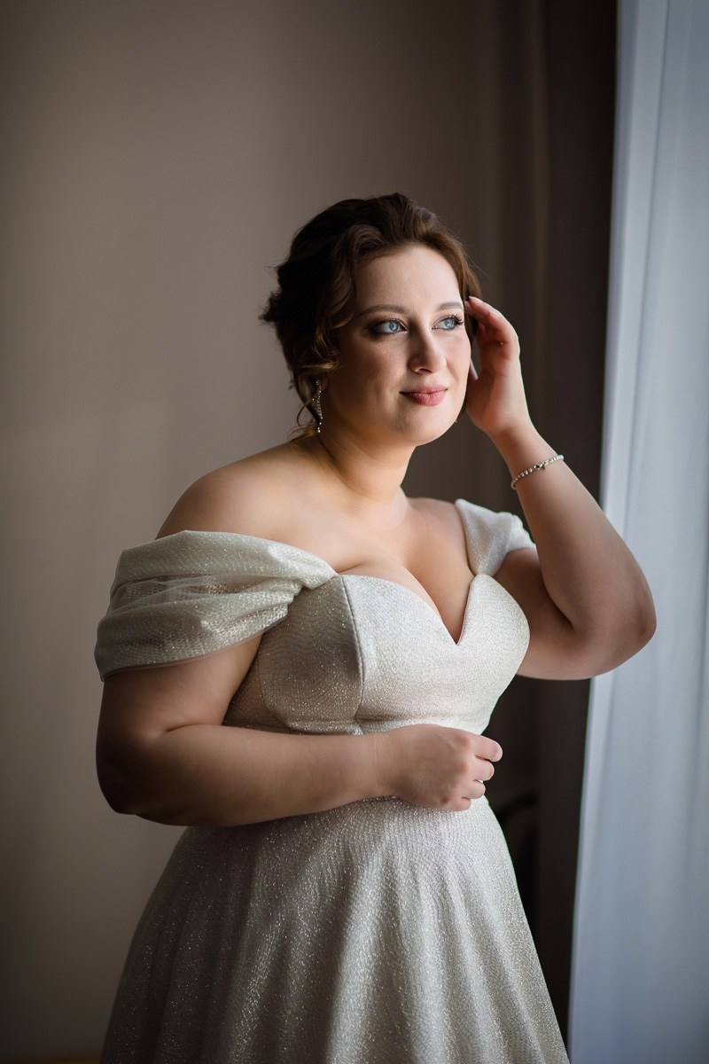 Невеста у окна поправляет причёску