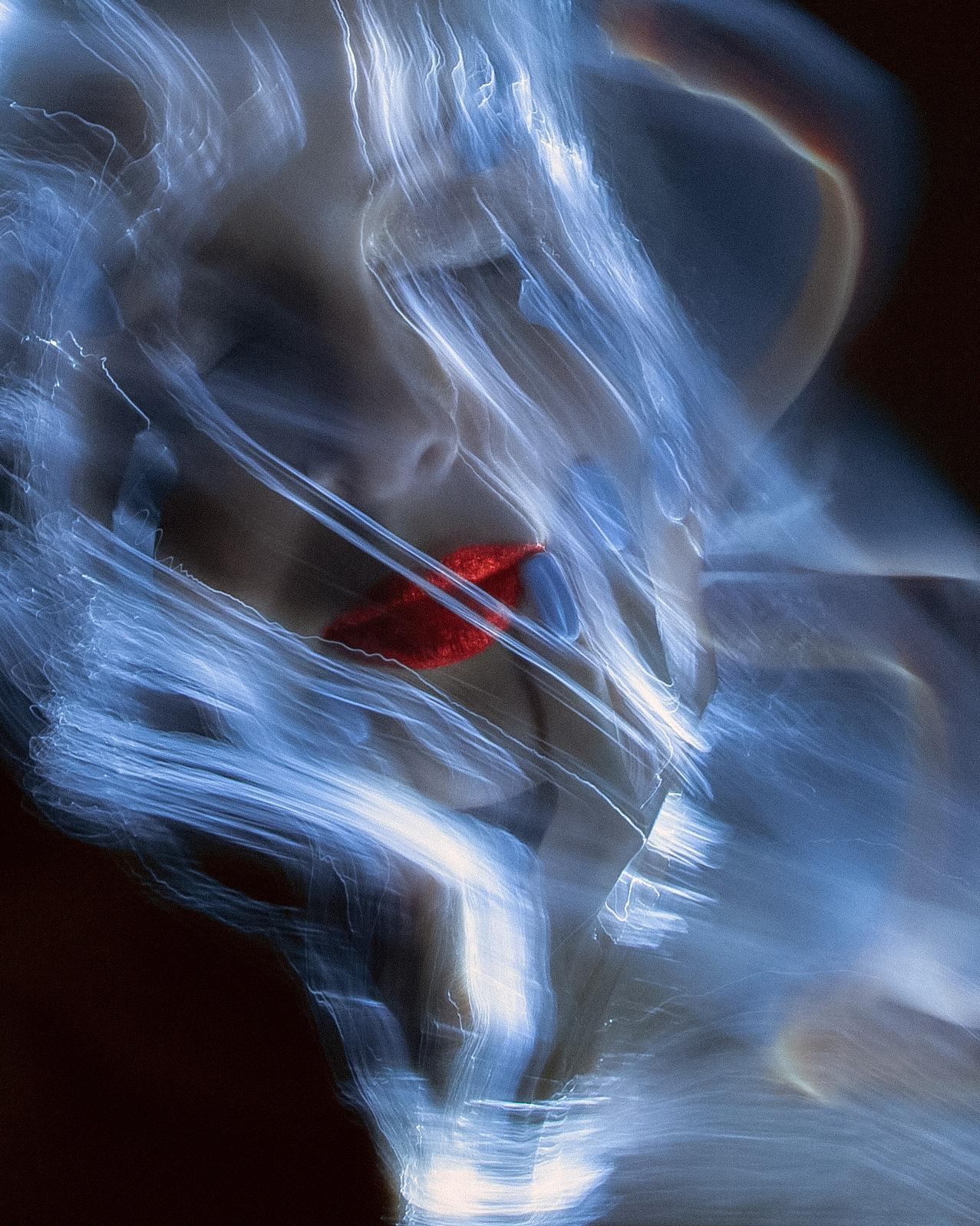 Фотография девушки с красными блестками на губах в лучах света