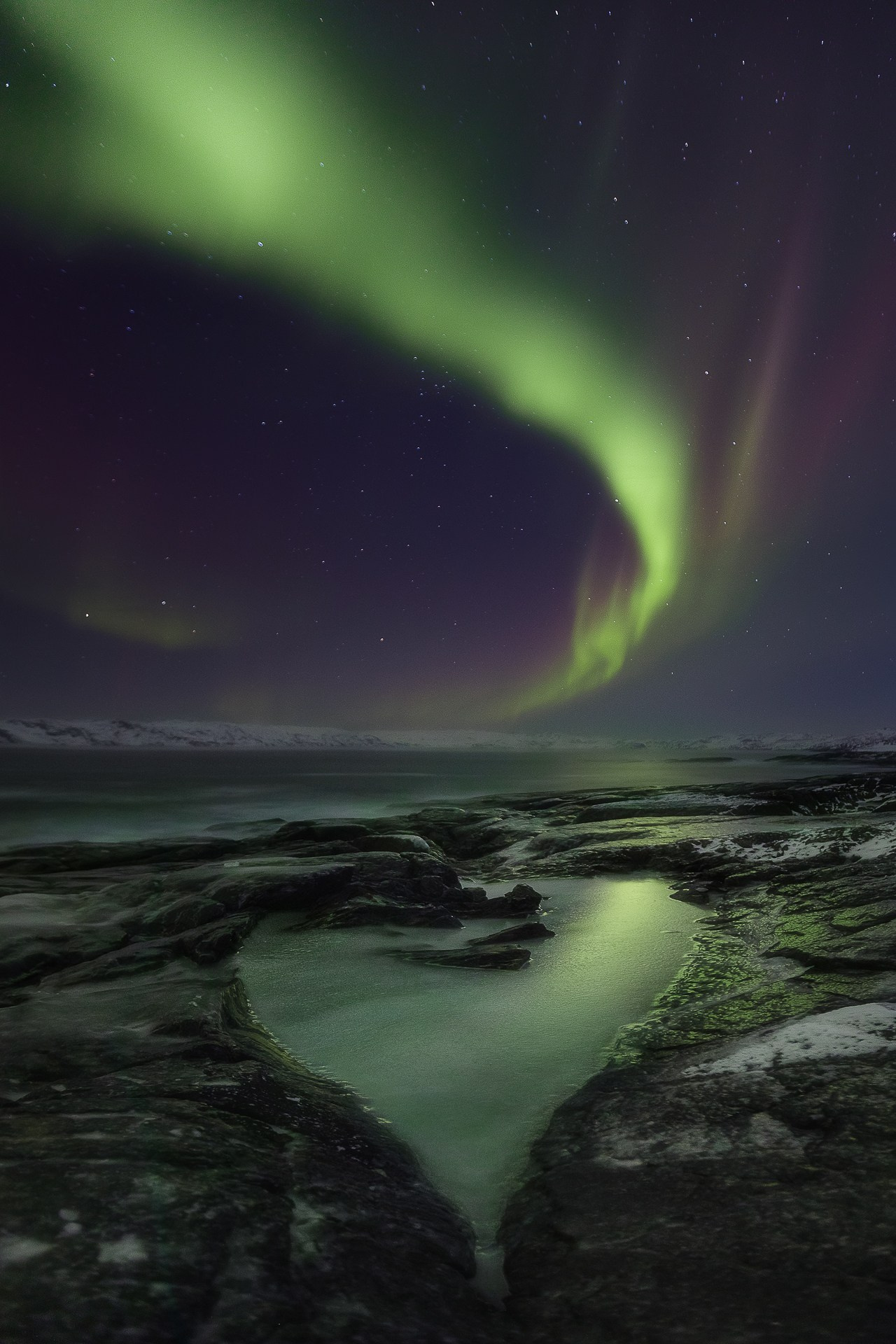 Северное сияние отражается в покрытой льдом луже в виде сердца