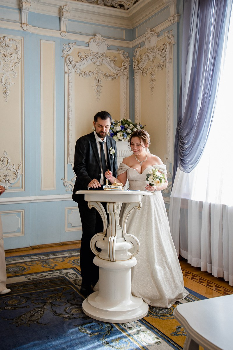 Жених и невеста в зале регистраций ставят подписи в ЗАГСе на фурштатской СПб. Горизонтальный кадр