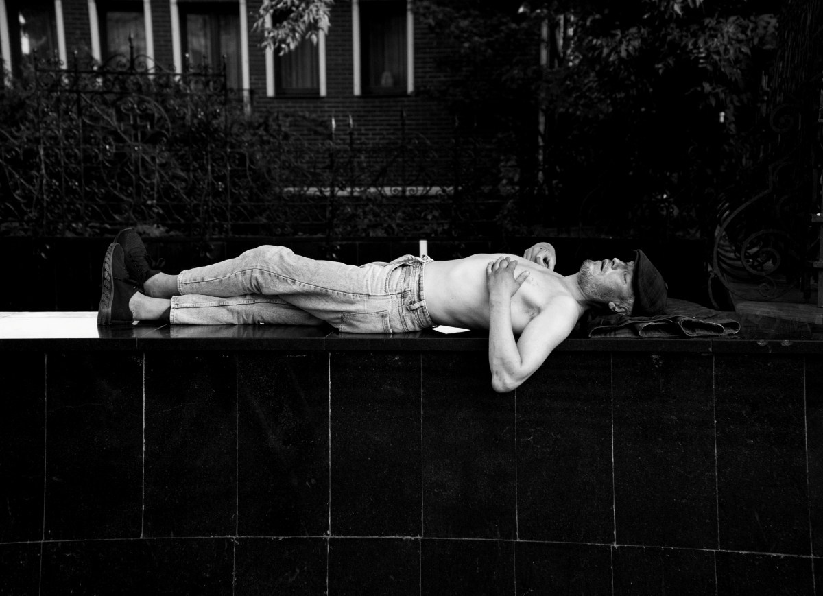 Черно-белая художественная фотография: обнаженный торс мужчины в светлых брюках лежит на темном бортике фонтана или бассейна, тело вытянуто, голова откинута назад, ночная атмосфера, уличная фотография Москвы, Вадим Топорёнок, Манифест теней, метафора перезагрузки, анатомия покоя, ночная съемка, городской минимализм.