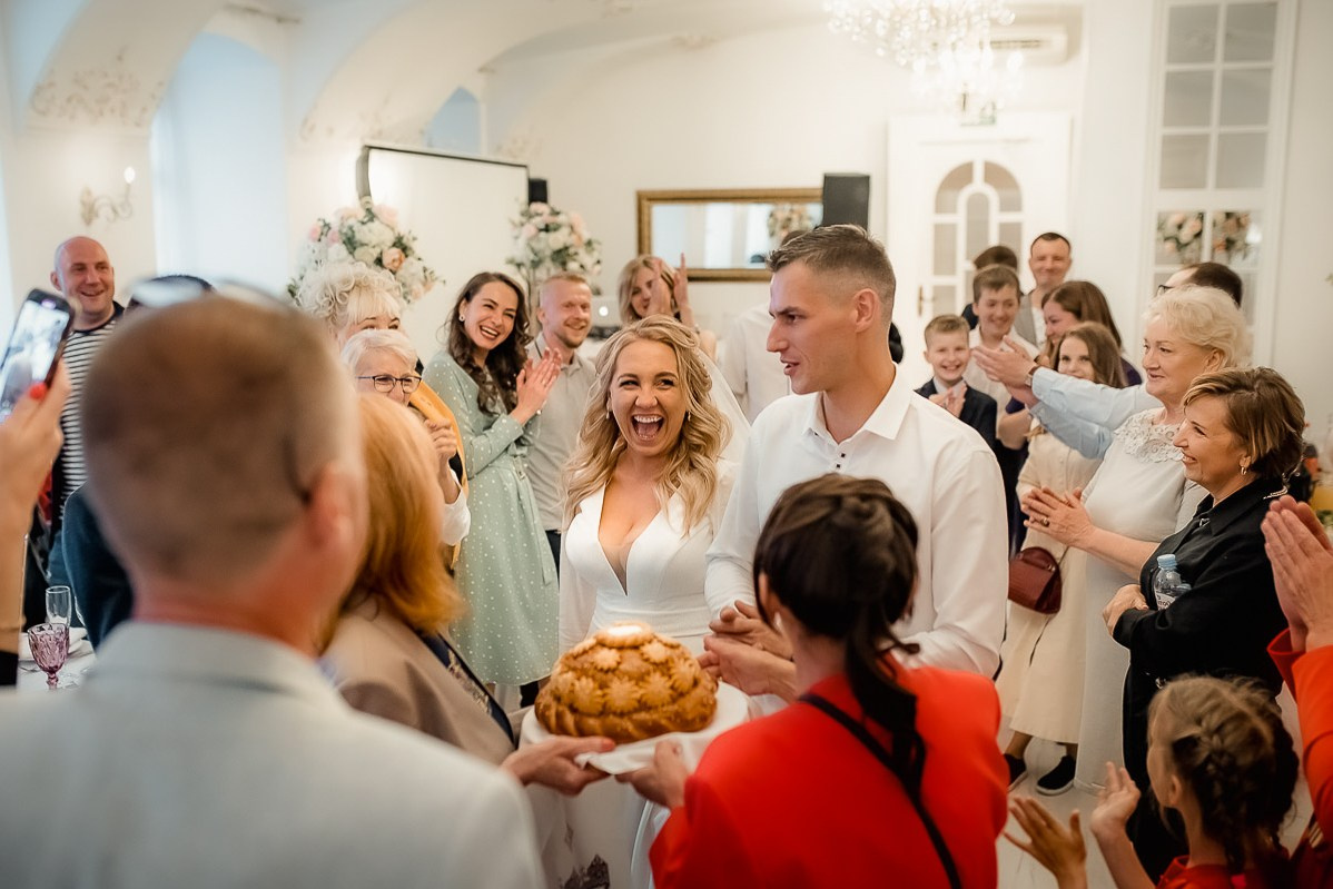 Жениха и невесту встречают хлебом и солью в ресторане в Санкт-Петербурге. Невеста смеётся. Горизонтальный  поясной кадр.
