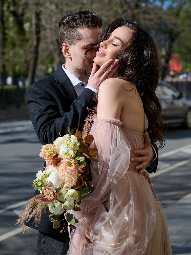 Свадебная фотосессия, жених обнимает и целует любимую жену