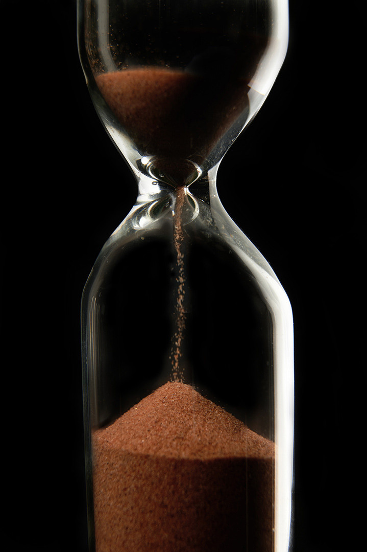 рекламная фотография, песочные часы на черном фоне