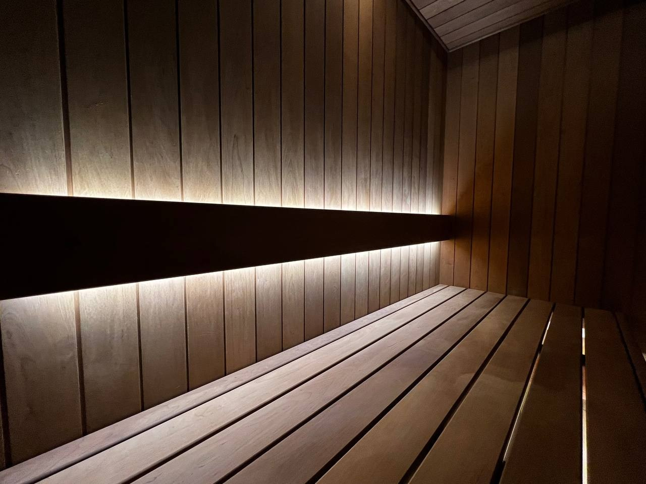 Компактная сауна в Охта Парке с электрокаменкой Harvia Cilindro, отделкой из термоольхи и сияющим можжевеловым панно. SaunaTopMasters