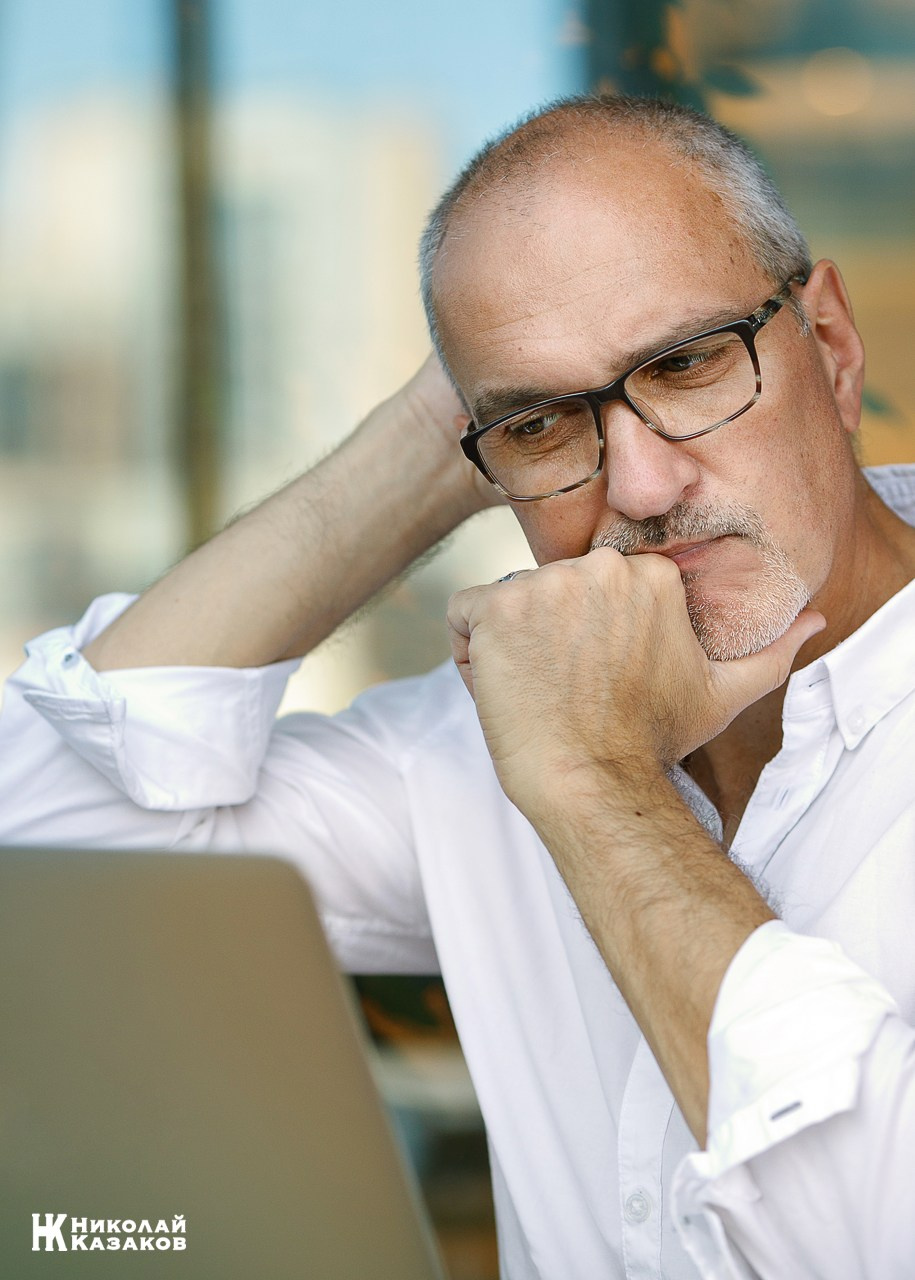 Бизнесмен в задумчивости смотрит в экран ноутбука подперев подбородок