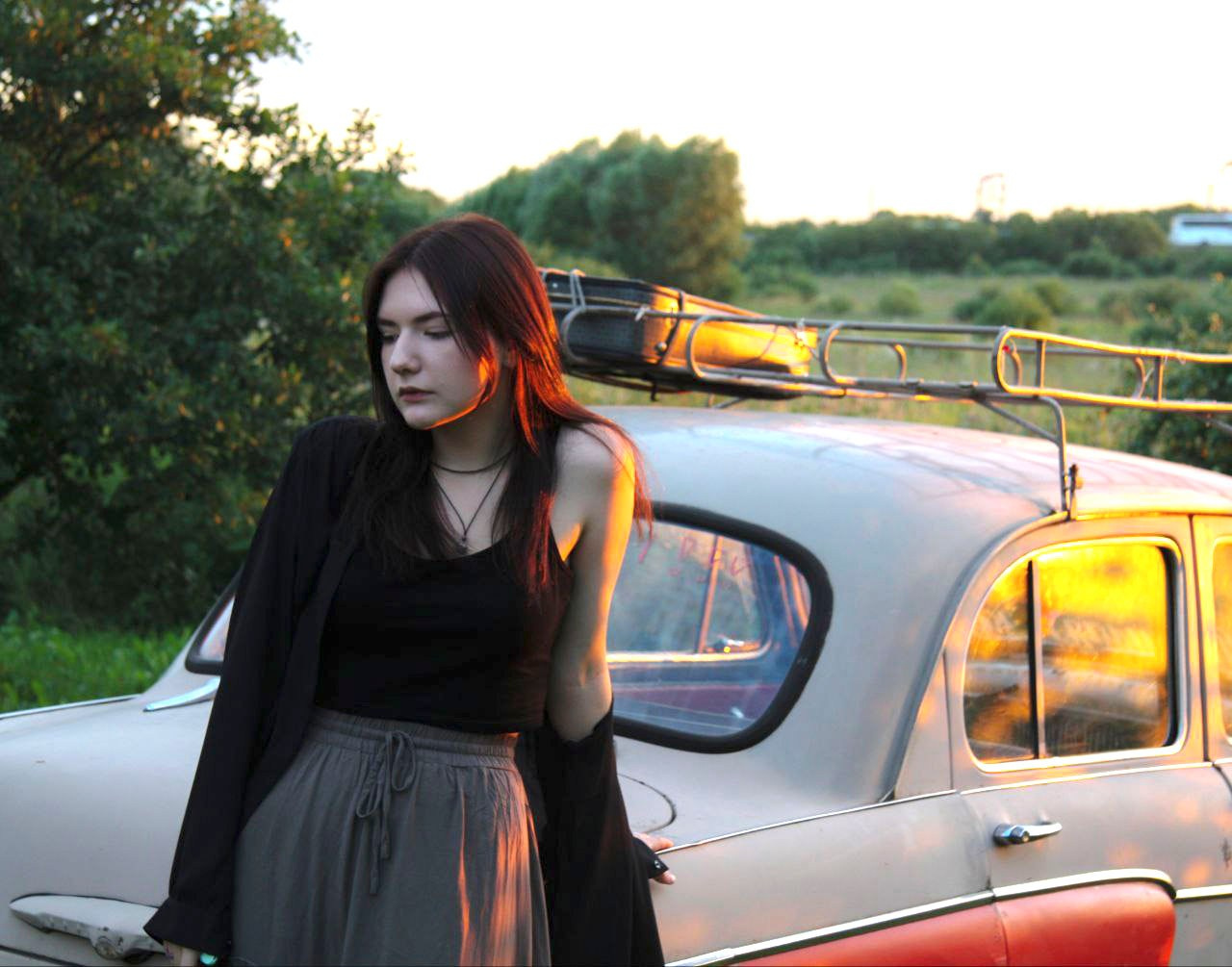 Летняя фотосессия девушки с естественным освещением на фоне машины в поле