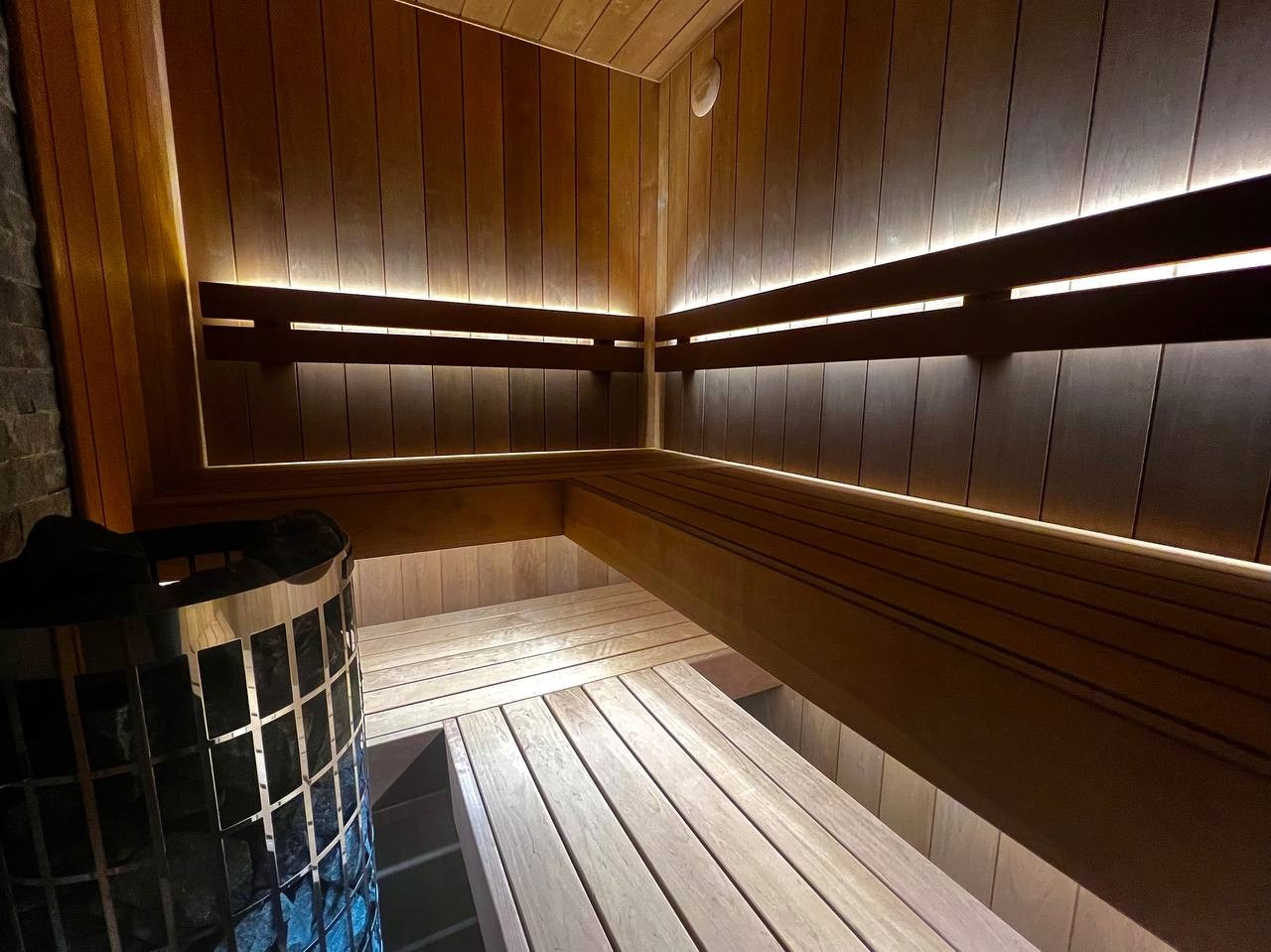 Семейная сауна на мансарде в Охта Парке: широкая термоольха, парящие полки и тёплая линейная подсветка для полного погружения. SaunaTopMasters