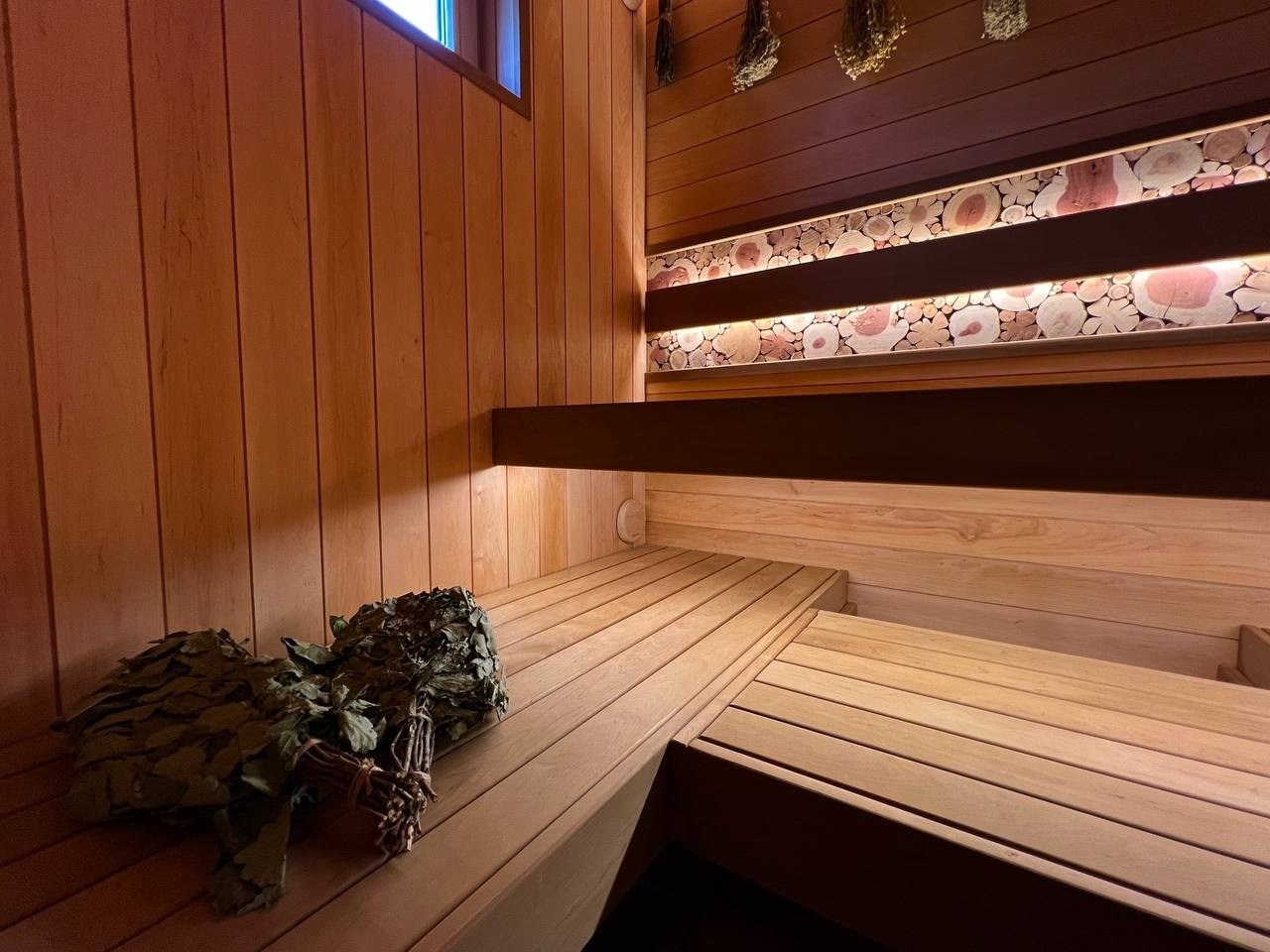 Семейная баня в Рощино из ольхи с можжевеловым панно, яркой печной зоной, закарнизной подсветкой и печью от производителя Aston. SaunaTopMasters