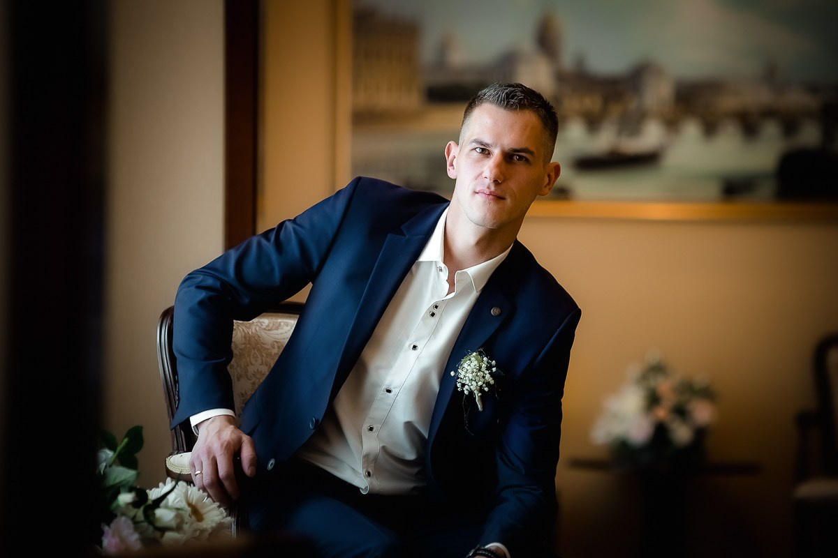 Жених сидя смотрит в кадр в ЗАГСе на Васильевском острове в Санкт-Петербурге. Горизонтальный кадр.