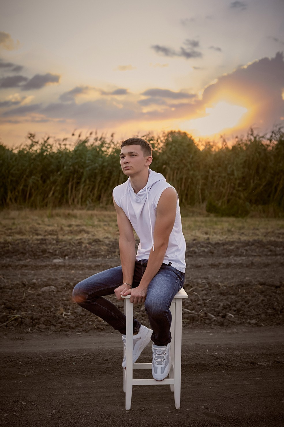 Фотограф в Москве. Креативное фото. Парень сидит на стуле в поле на закате.