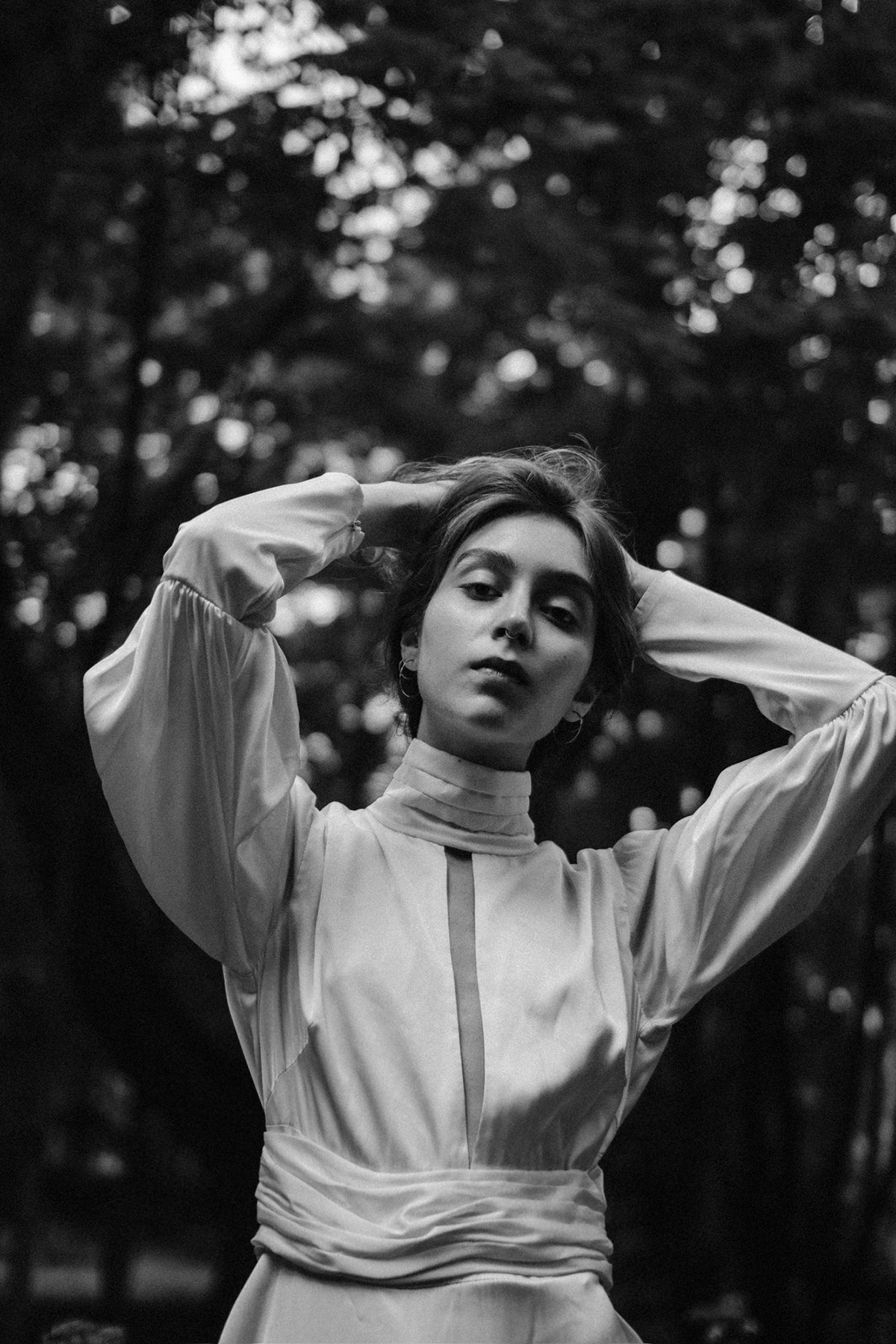 Девушка в белом шелковом платье поправляет волосы