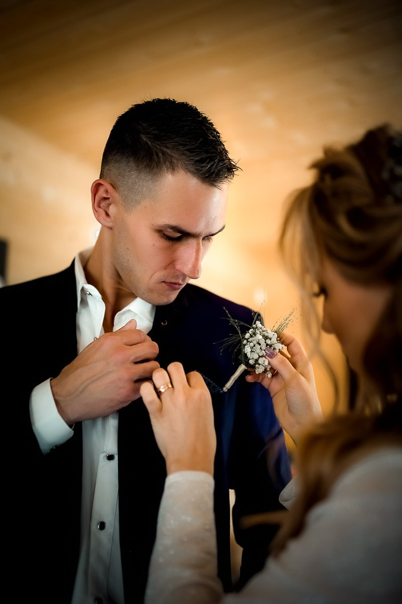 Жениху надевают бутоньерку в комнате в Санкт-Петербурге.