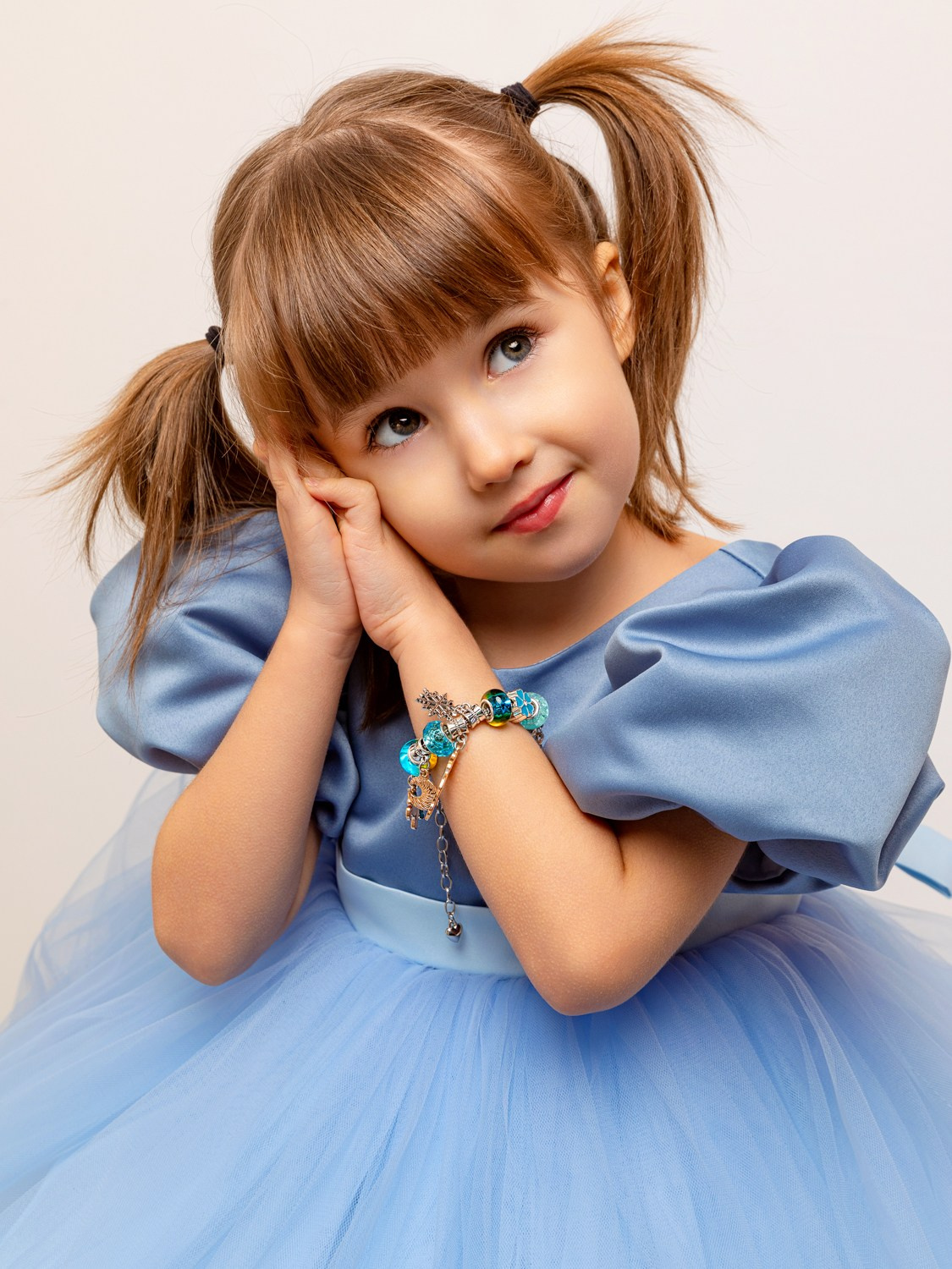 Девочка прижала руки к лицу, на правой руке браслет.