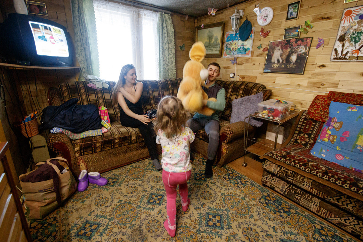 Папа и мама играют с дочкой.