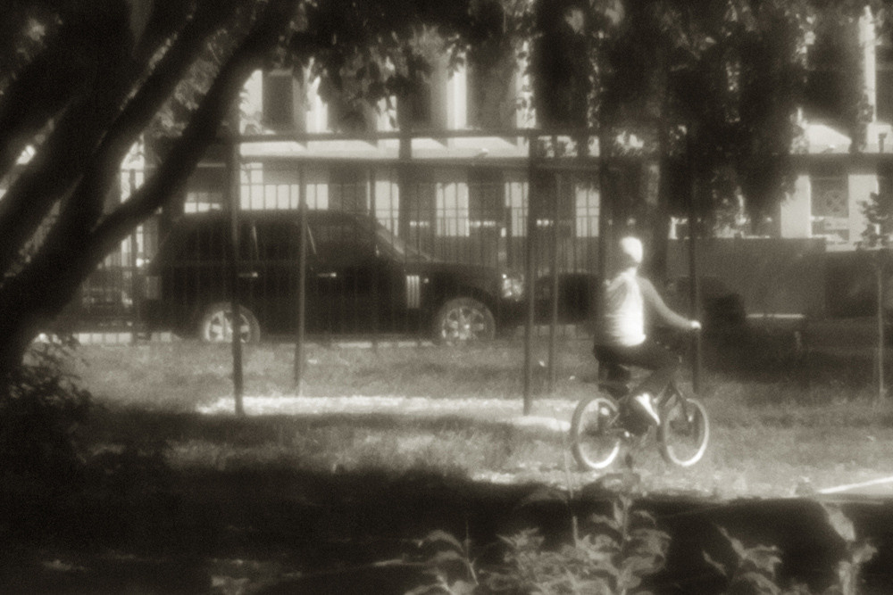 Чёрно-белое фото, мальчик на велосипеде. Велосипед и машина. Снято на монокль.