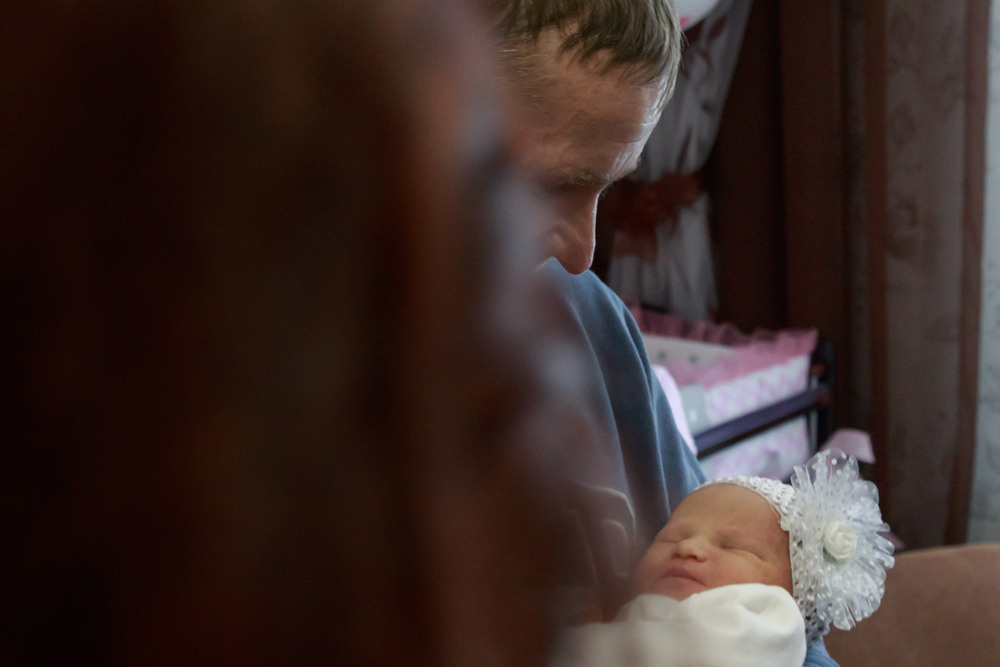 Мужчина держит на руках младенца.