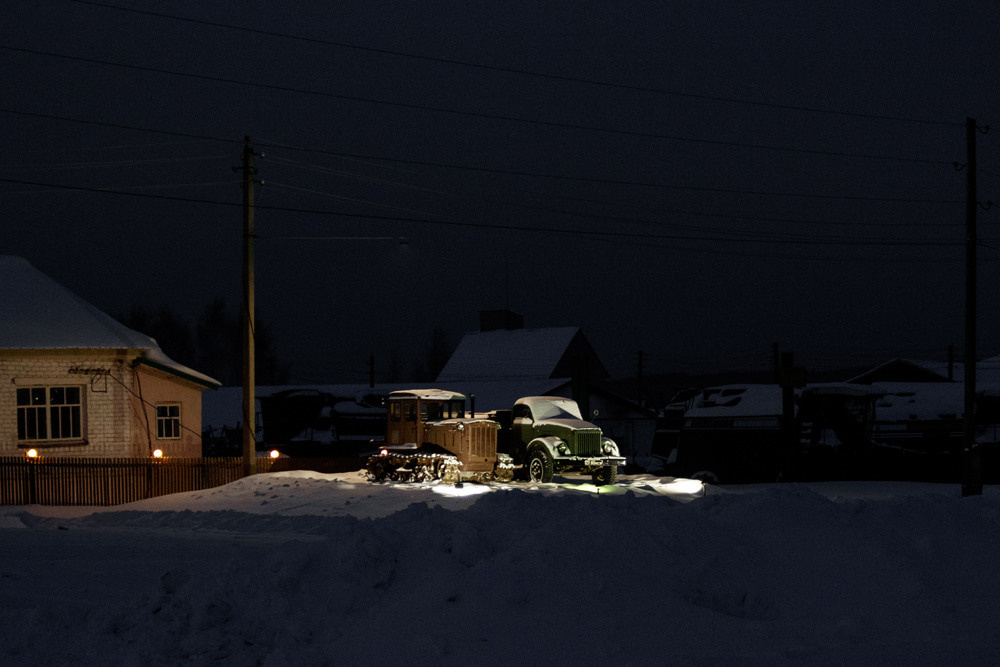 Старые трактор и грузовик ночью под фонарём