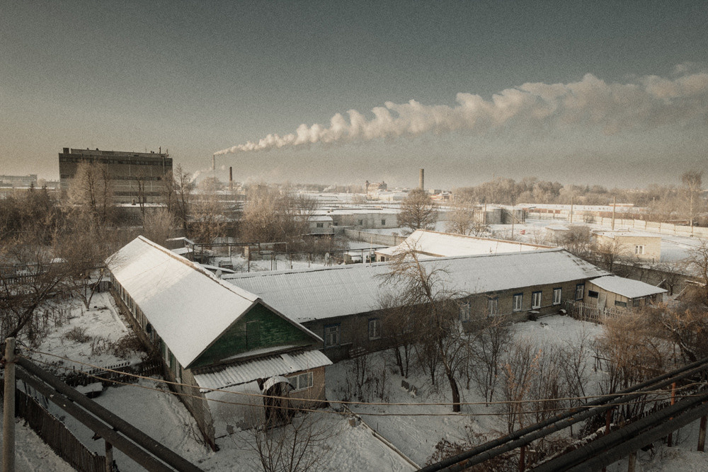 Городской пейзаж с моста. В далеке высокая труба из которой идёт дым.