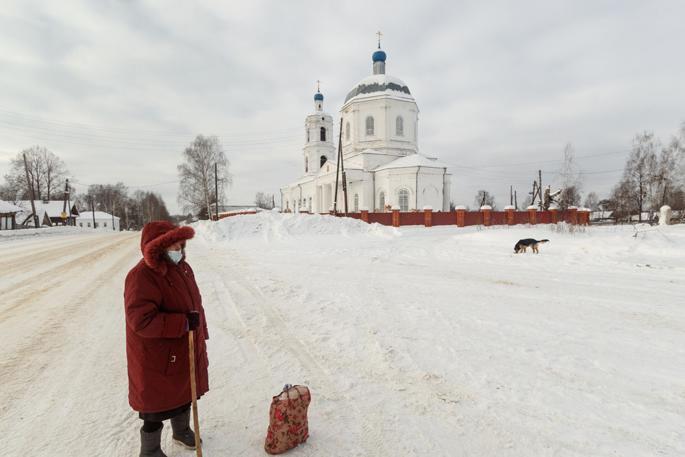 Женщина с сумкой стоит на фоне церкви.
