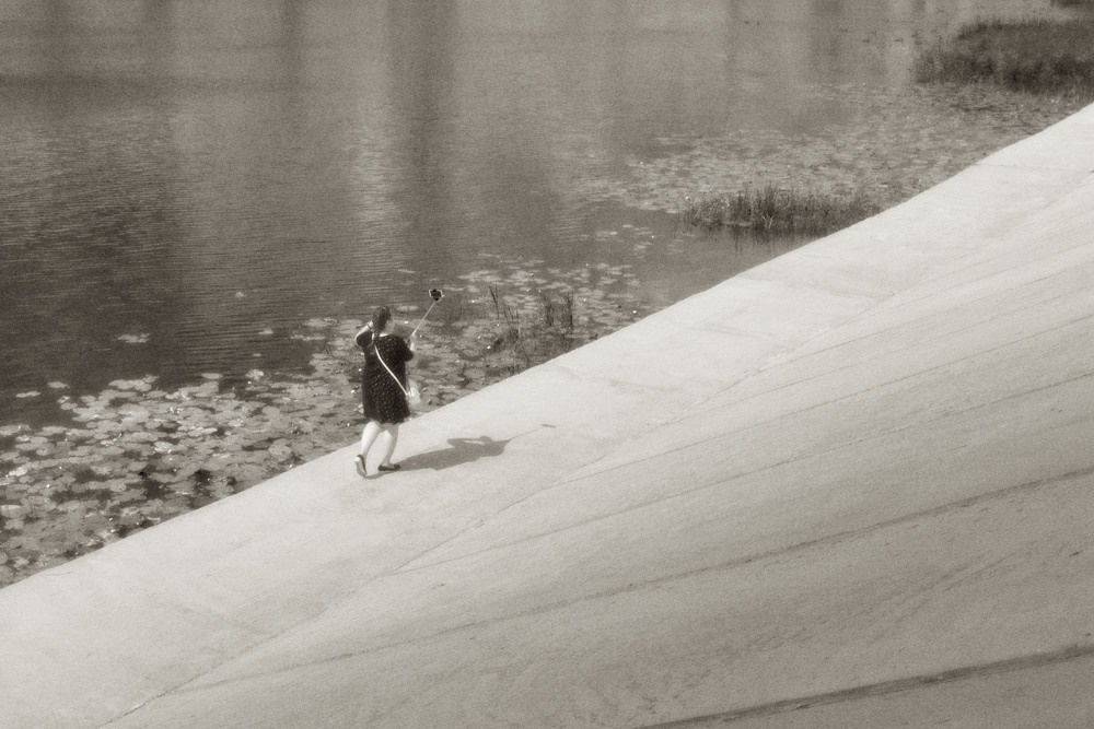 Черно-белое фото, девочка с телефоном, селфи на набережной.