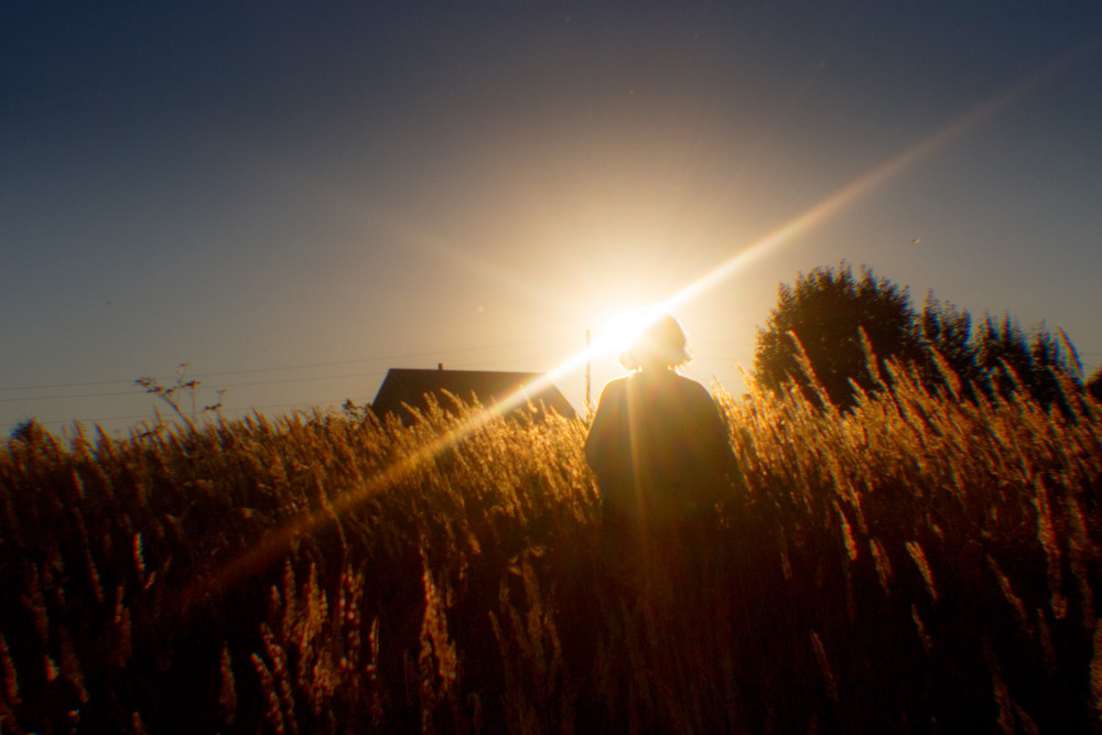 Лучи солнца в деревне в поле и силуэт женщины.