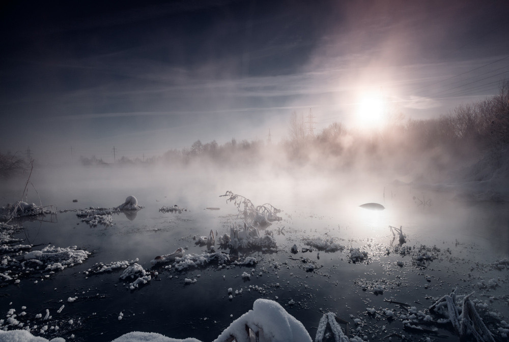 Контрастная зимняя фотография пруда, над которым густой пар.