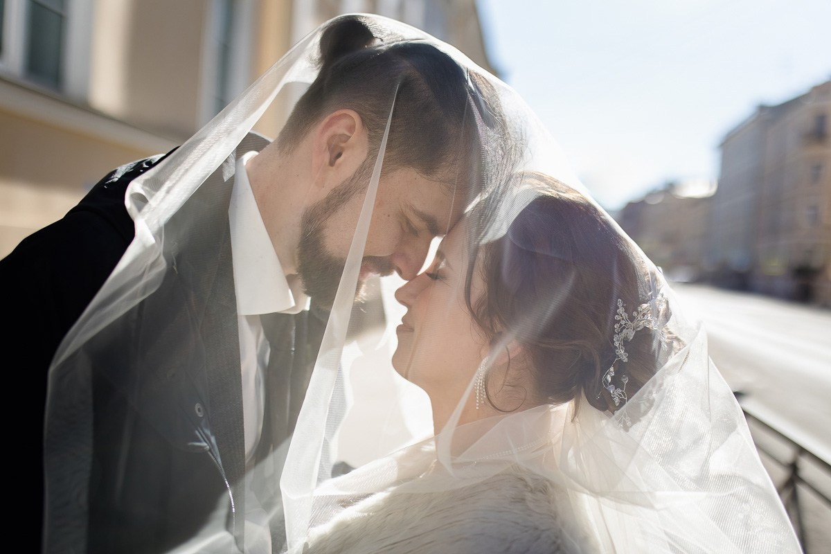 Жених и невеста под фатой прикасаются лбами