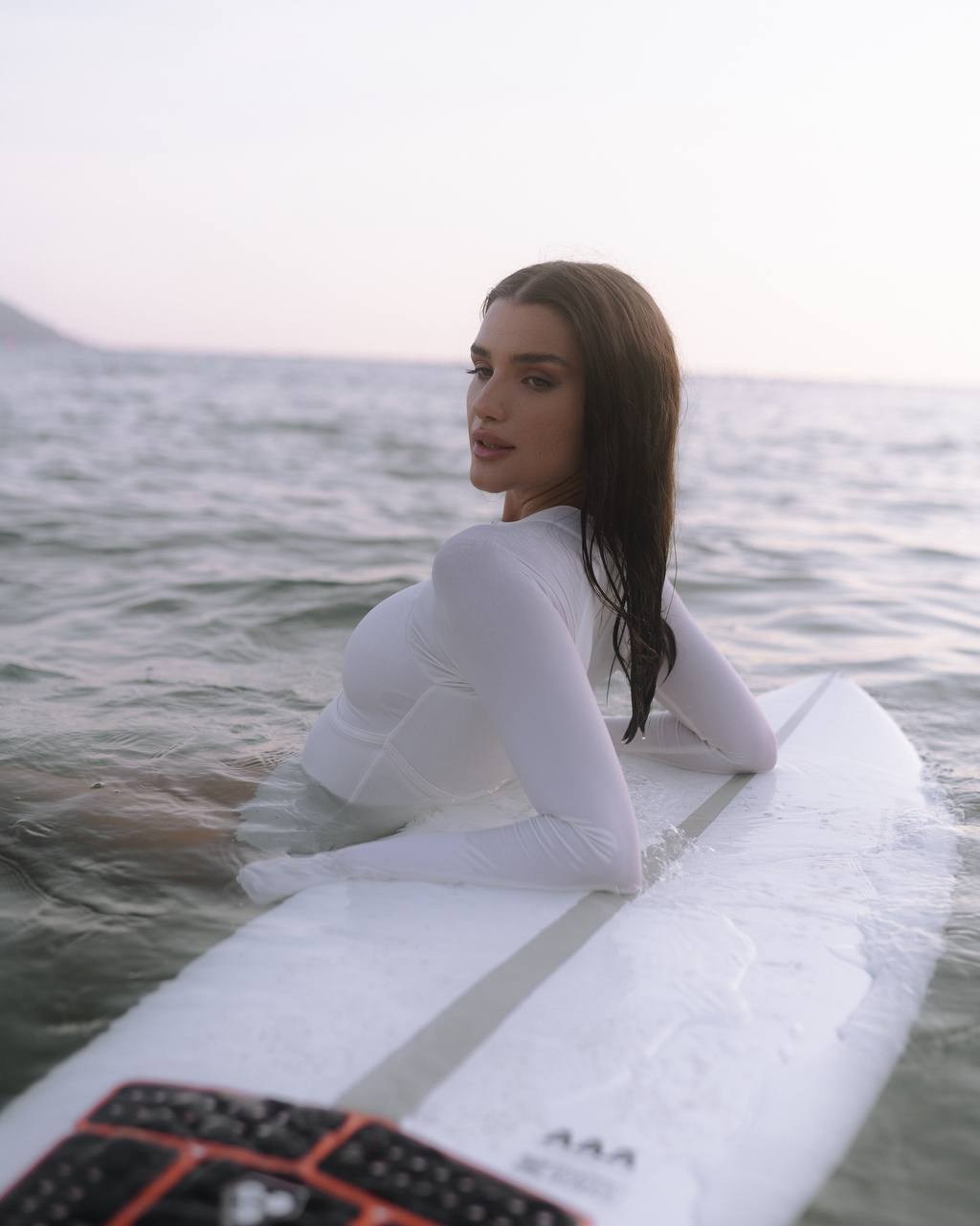 Девушка с доской в воде — спокойный кадр у моря