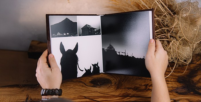 Фотокнига в раскрытом виде: на развороте черно-белые фотографии гор и лошадей. Демонстрация качественной печати и раскрытия страниц на 180 градусов.